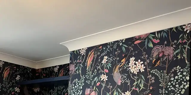 Feature wallpaper and navy painted shelving in a living room