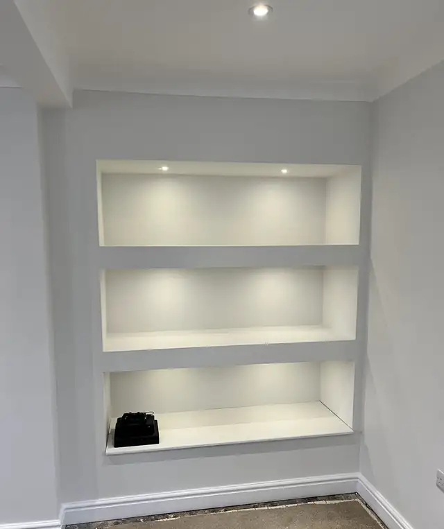 Lit alcove shelves and pale grey walls with white skirting, freshly decorated
